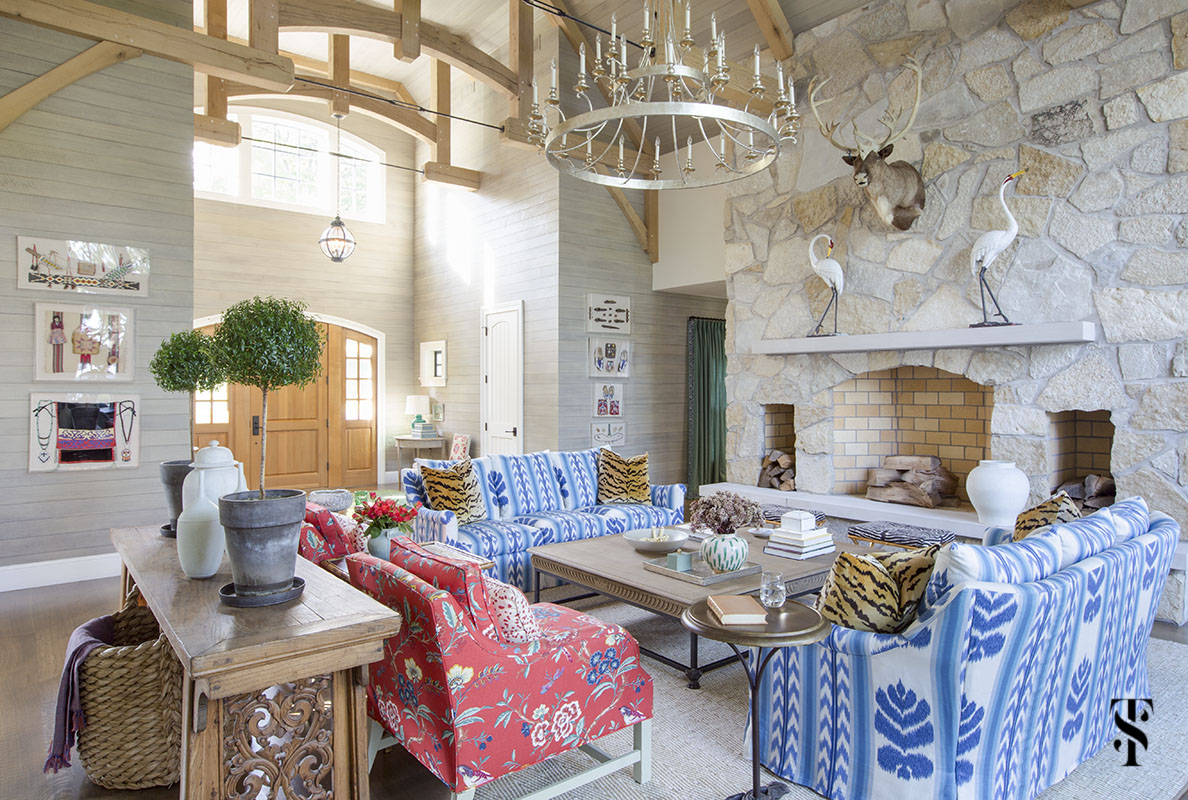 wisconsin lake house interior design by summer thornton with blue ikat sofa in Brunschwig & Fils Chenonceaux, vaulted ceiling with exposed beams and stone fireplace wall with elk taxidermy. www.summerthorntondesign.com