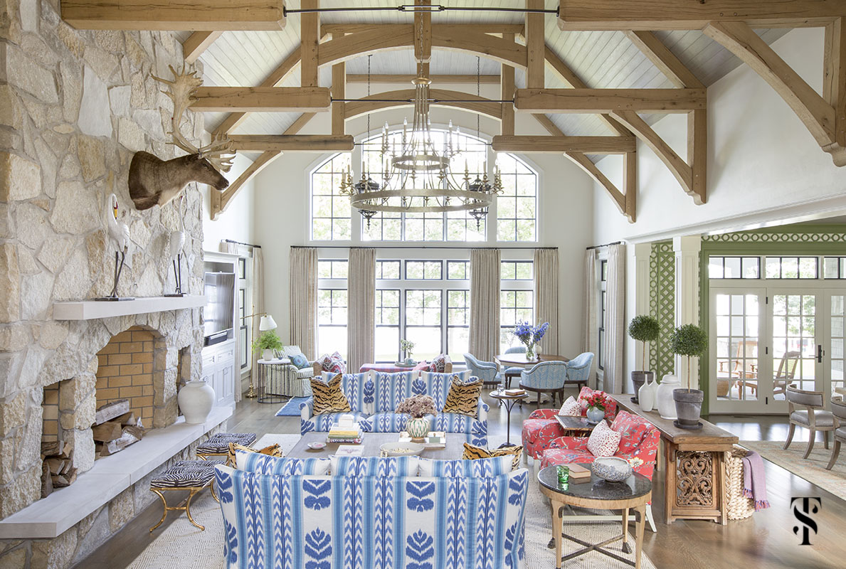 wisconsin lake house interior design by summer thornton with blue ikat sofa in Brunschwig & Fils Chenonceaux, vaulted ceiling with exposed beams and stone fireplace wall with elk taxidermy. www.summerthorntondesign.com