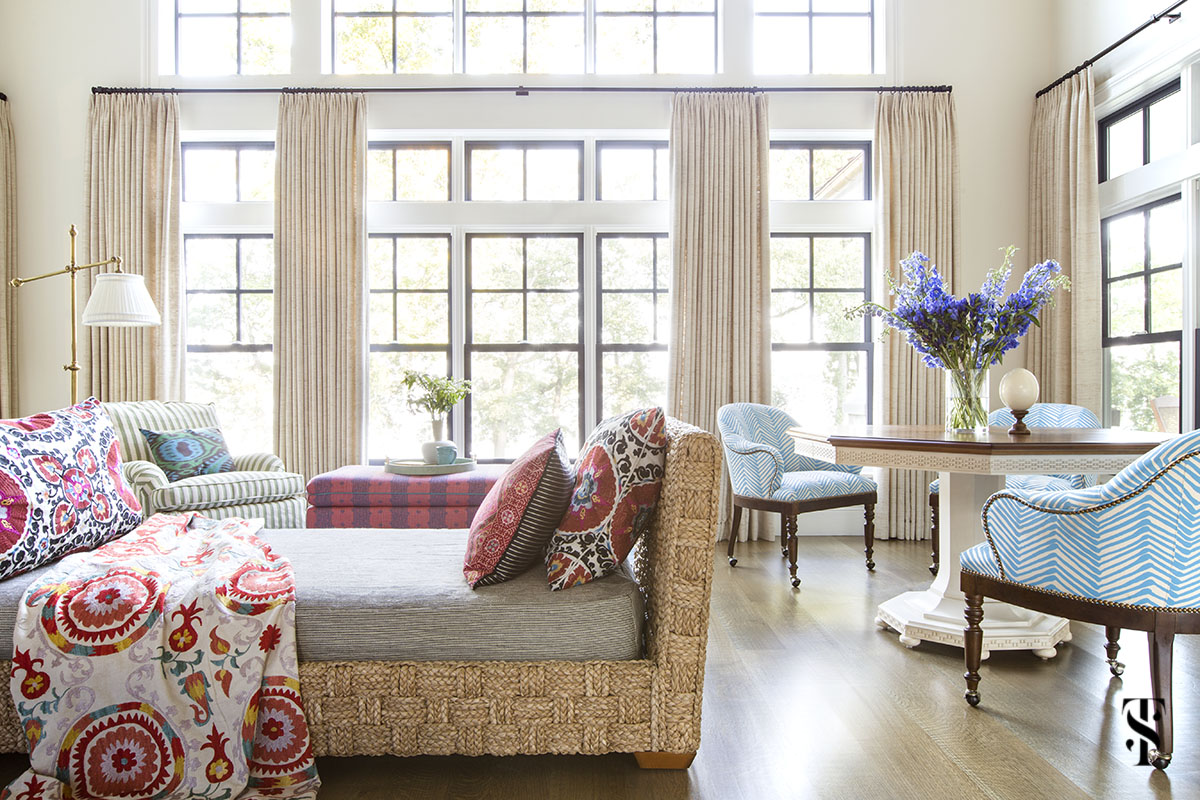wisconsin lake house interior design by summer thornton with jute daybed, ethnic pattern pillows, and game table overlooking the lake through a wall of windows. www.summerthorntondesign.com