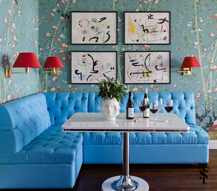 Breakfast & dining area designed by Summer Thornton featuring F Schumacher Miles Redd Brighton Pavillion wallpaper, red sconce shades, Joan Miro artwork and a bright blue banquette. Summer Thornton Interior Design works on projects nationwide from her Chicago interior design office headquarters.