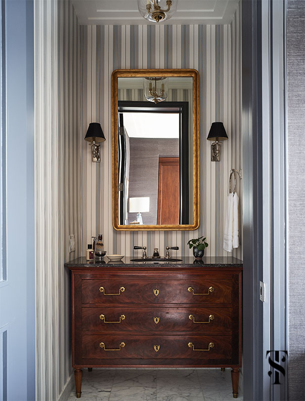 A masculine bathroom with black and white striped wallpaper and antique chest as vanity designed by Summer Thornton. For more photos visit www.SummerThorntonDesign.com