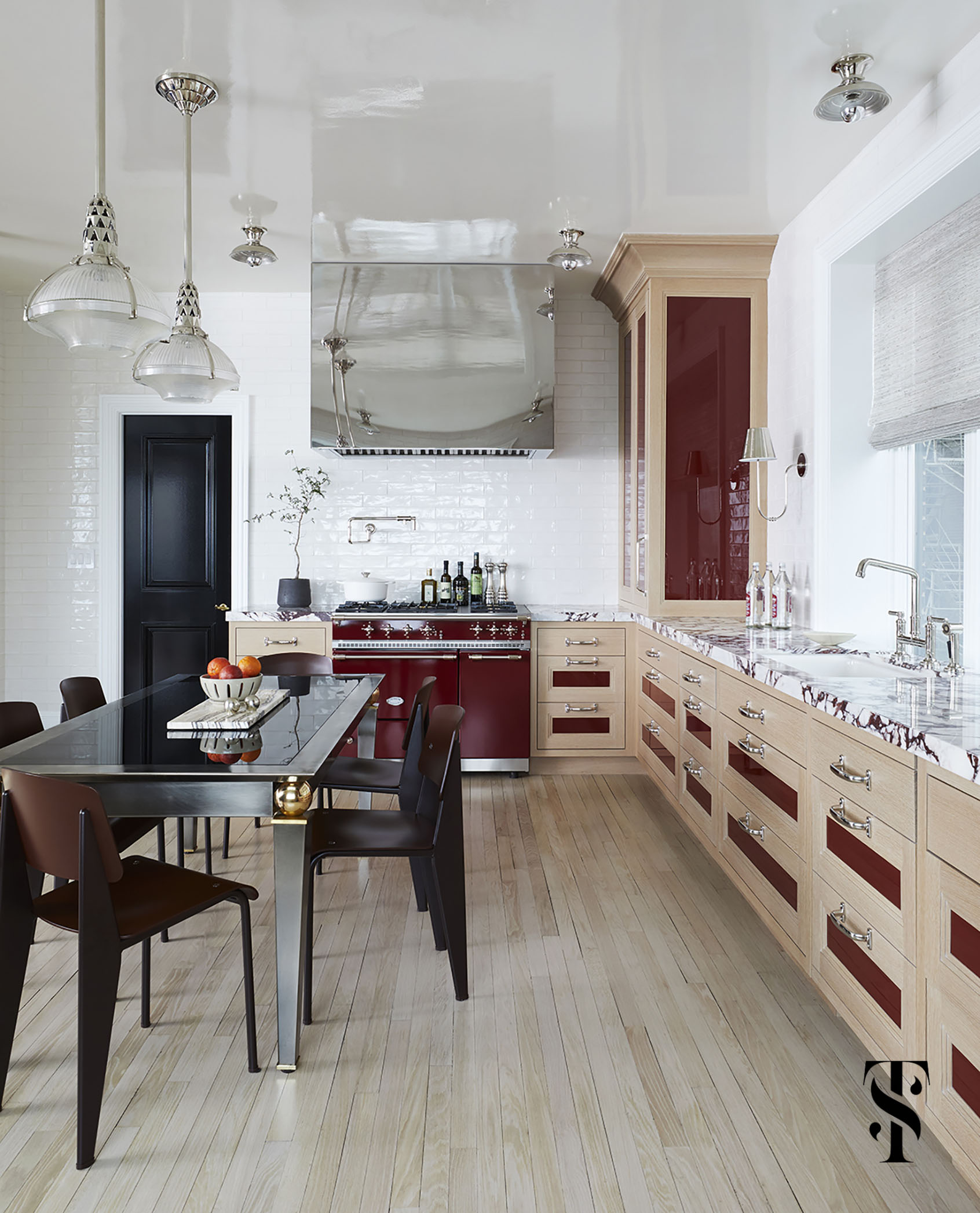 glossy details from a mirror-finish polished stainless steel hood to high-gloss cabinetry inserts in burgundy red & even a lacquered ceiling give this kitchen by interior designer Summer Thornton a water-like reflective quality, emulating the waves of Lake Michigan that it overlooks