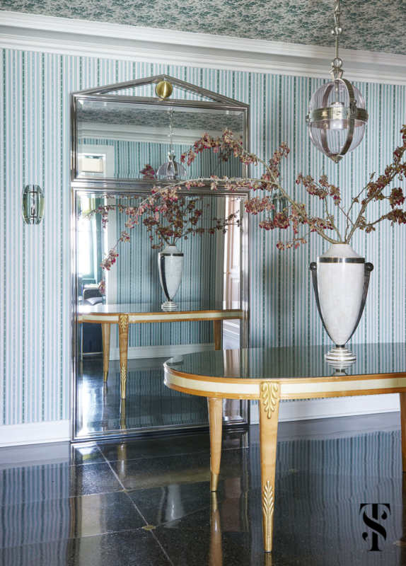 An entry foyer designed by Summer Thornton featuring a custom designed mirror in polished nickel and lilac glass, pendant by Urban Electric, and Gucci wallpapered ceiling.