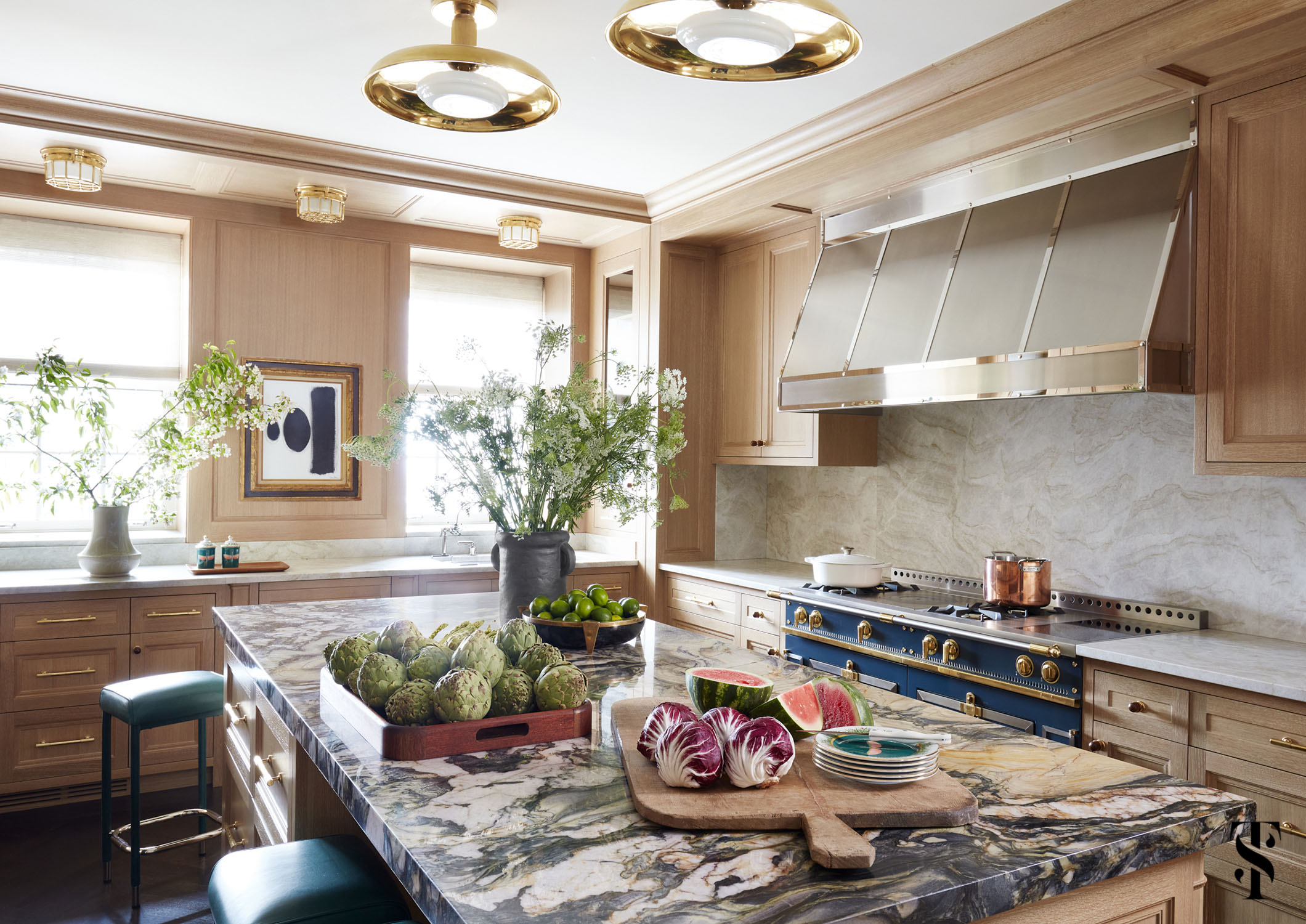 This moody kitchen features a La Cornue range, Crillon stools by Soane, ceiling flush mounts by Roman and Williams Guild, and explosion marble on the island.