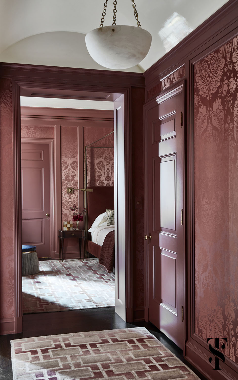 A sultry master bedroom entry hall featuring de Gournay pineapple demask in raspberry, & a walnut bed from Dennis Miller Associates