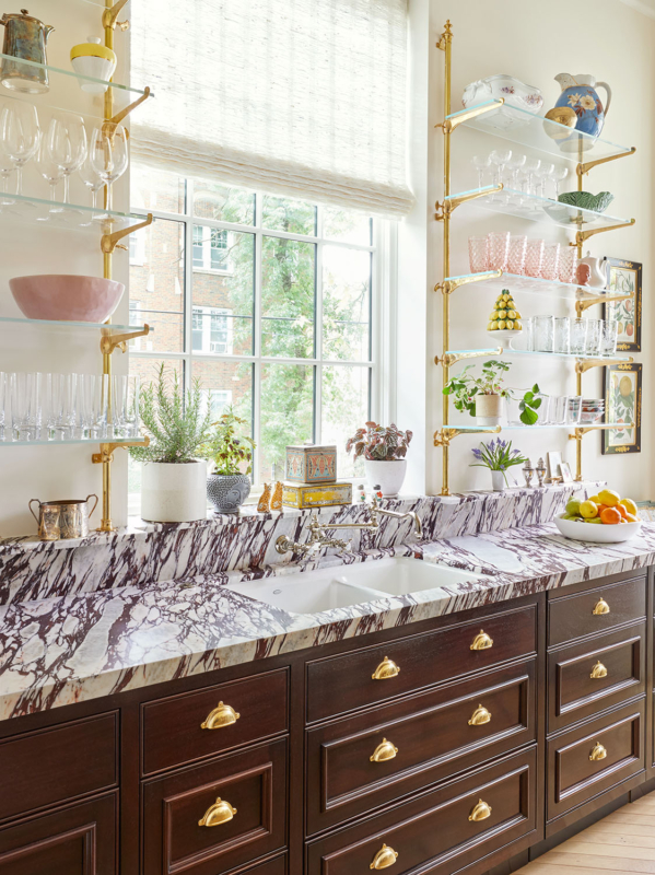 Summer Thornton’s personal Chicago residence designed by Summer Thornton. Kitchen features glass and brass shelves, mahogany cabinetry, prunella countertops and backsplash and a 17th century marble fireplace.
