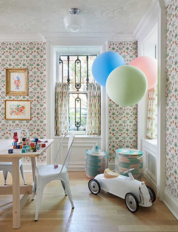 Summer Thornton’s personal Chicago residence designed by Summer Thornton. Play room features pink and green floral wallpaper that matches the same patterned drapes, a maple wooden craft table and a fonrasetti wall covering on the ceiling.